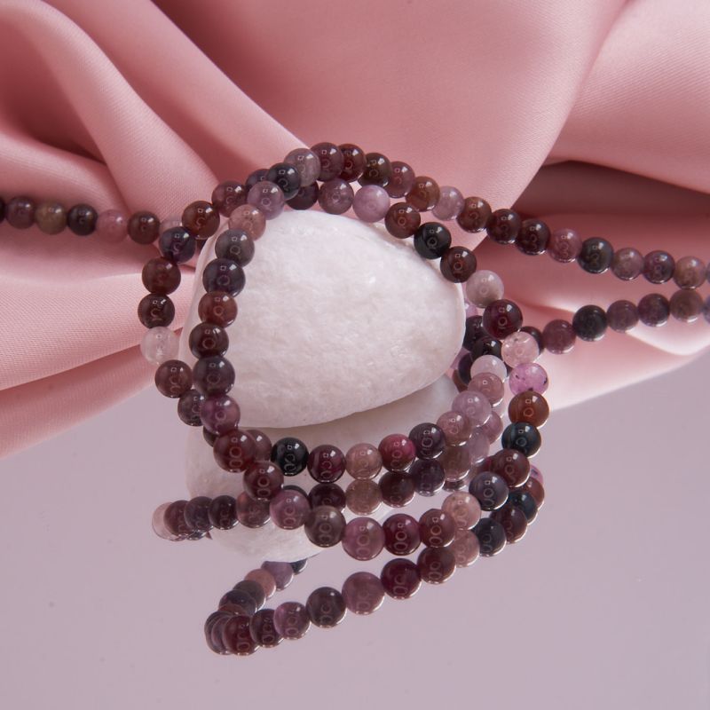Nahaufnahme einer hochwertigen, glatt geschliffenen Multicolor-Spinellkette mit Edelsteinen in Rosa, Rot, Grau und Schwarz.